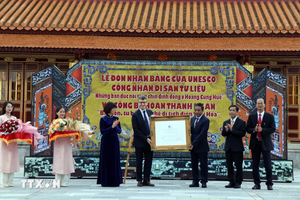 Trưởng Đại diện Văn phòng UNESCO tại Việt Nam Jonathan Wallace Baker trao Bằng công nhận di sản tư liệu khu vực châu Á-Thái Bình Dương của UNESCO đối với “Những bản đúc nổi trên chín đỉnh đồng ở Hoàng cung Huế” cho phía Việt Nam. (Ảnh: Đỗ Trưởng/TTXVN)