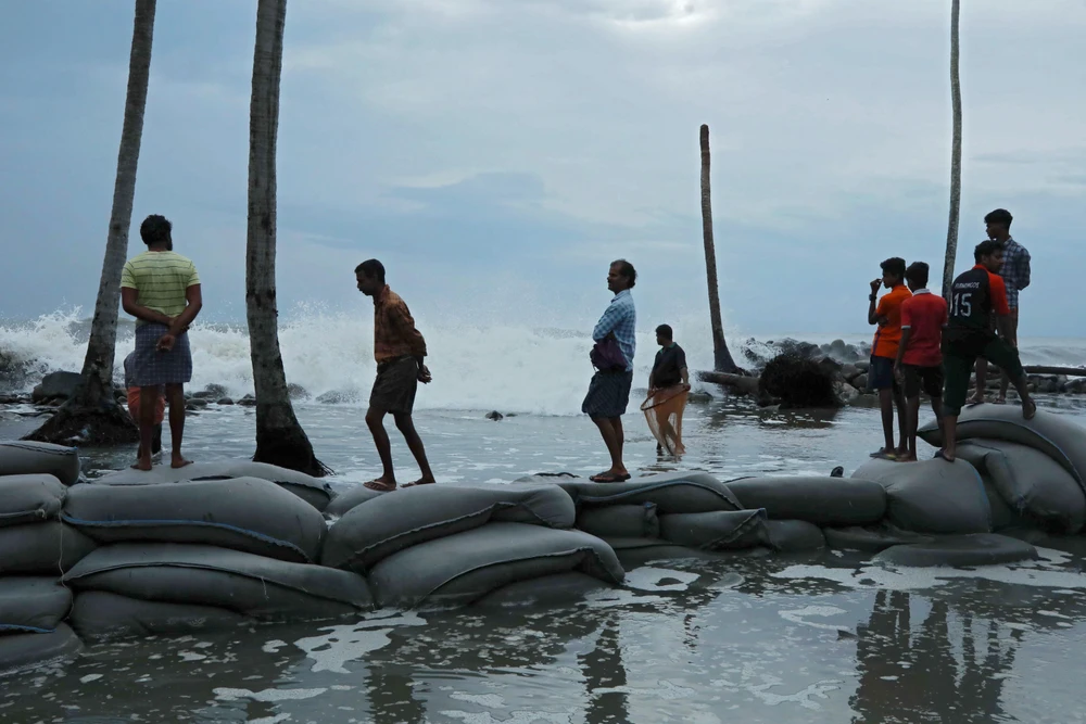 Người dân đặt bao cát ngăn các con sóng lớn do ảnh hưởng của bão Maha tại Chellanam, Ấn Độ. (Ảnh: AFP/TTXVN)