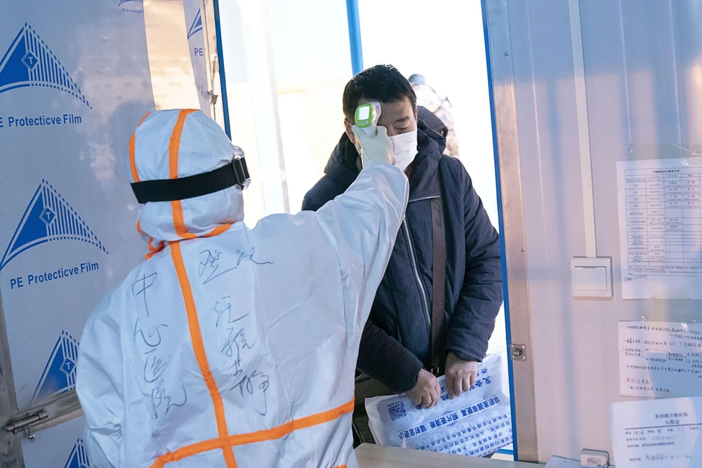 Nhân viên y tế kiểm tra thân nhiệt cho bệnh nhân nhiễm nCoV tại một bệnh viện dã chiến ở Vũ Hán, Trung Quốc. (Ảnh: THX/TTXVN)