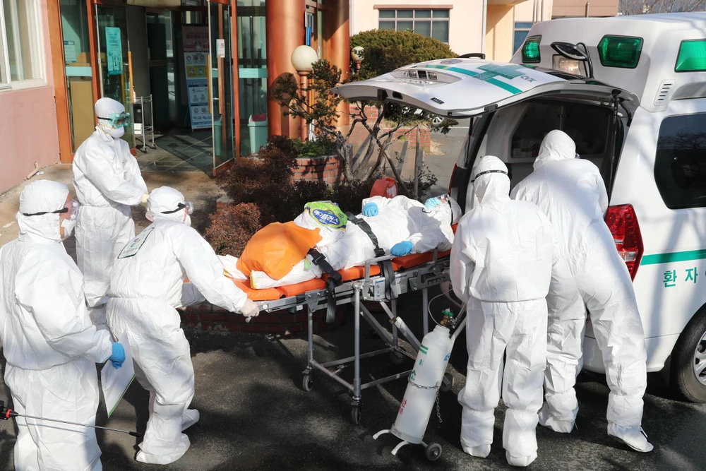 Nhân viên y tế chuyển bệnh nhân nhiễm virus SARS-CoV-2 lên xe cứu thương tại thành phố Daehu, Hàn Quốc. (Ảnh: AFP/TTXVN)