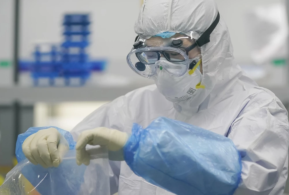 Kỹ thuật viên xử lý mẫu xét nghiệm axit nucleic tại một phòng thí nghiệm về virus SAR-CoV-2 ở Vũ Hán, Trung Quốc. (Ảnh: THX/TTXVN)