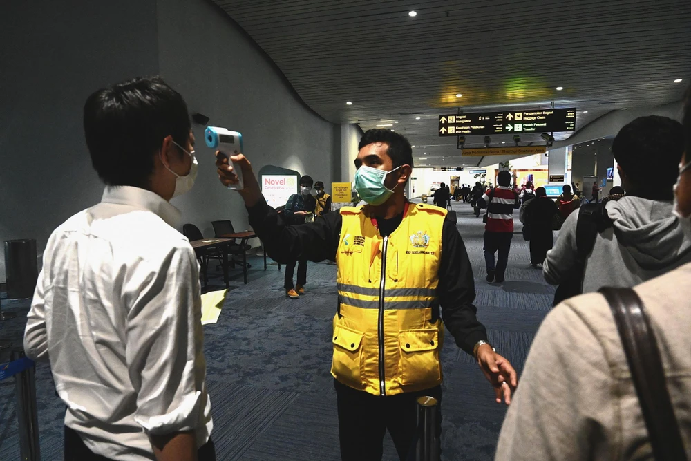 Nhân viên y tế Indonesia kiểm tra thân nhiệt hành khách tại sân bay quốc tế Jakarta nhằm ngăn chặn sự lây lan của dịch bệnh COVID-19. (Ảnh: AFP/TTXVN)