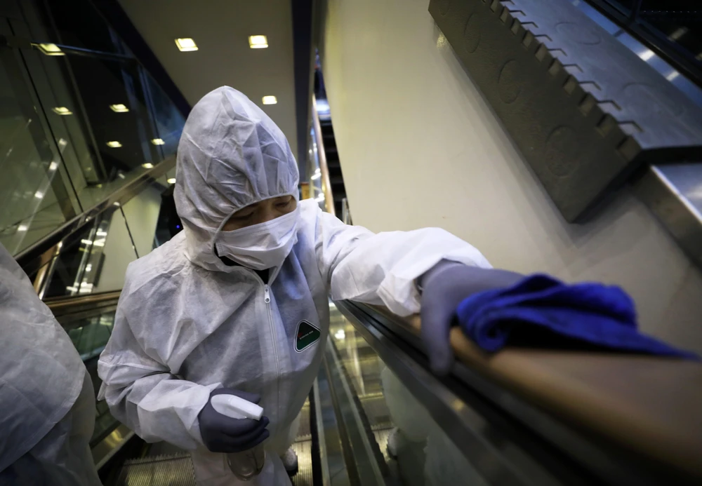 Nhân viên khử trùng tay nắm cầu thang tại một trung tâm thương mại ở Seoul, Hàn Quốc nhằm ngăn chặn sự lây lan của COVID-19. (Ảnh: THX/TTXVN)