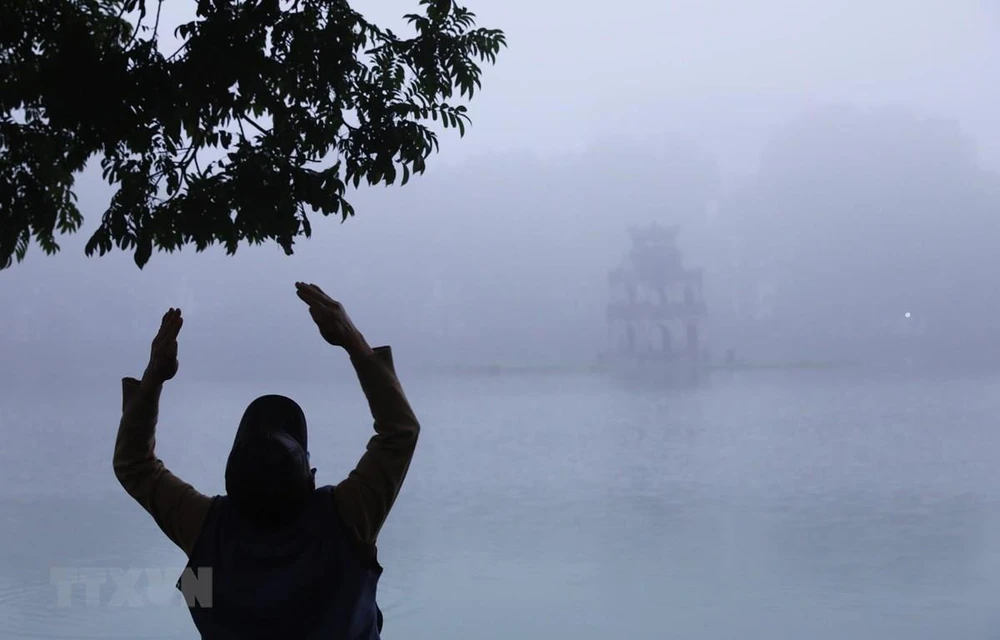 Một dân tập thể dục bên hồ Hoàn Kiếm, Hà Nội trong sương sớm. (Ảnh: Lâm Khánh/TTXVN)