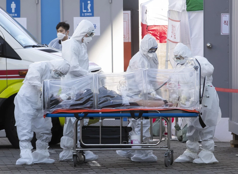 Nhân viên y tế chuyển bệnh nhân nhiễm COVID-19 tới bệnh viện ở Seoul, Hàn Quốc, ngày 11/3. (Ảnh: THX/TTXVN)