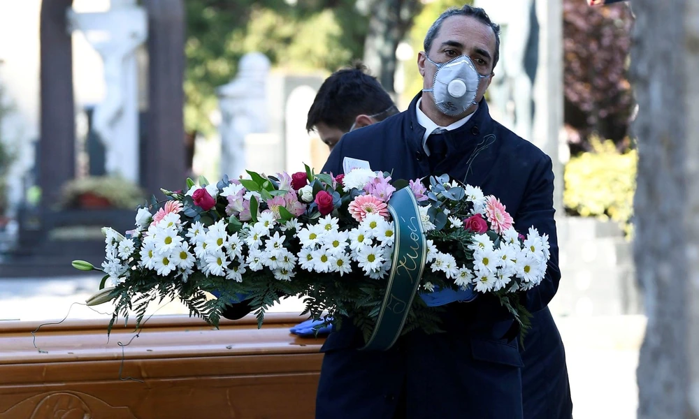 Nhân viên nhà tang lễ vận chuyển quan tài của một nạn nhân nhiễm virus SARS-CoV-2 vào một nghĩa trang ở Bergamo. (Ảnh: Reuters)