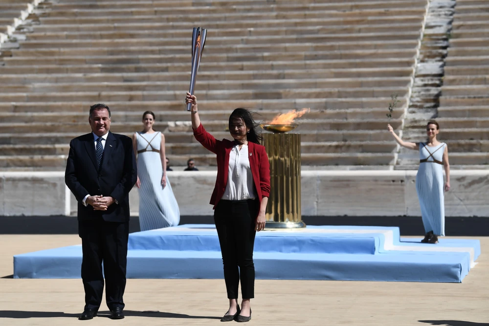 Bộ trưởng Thể thao Hy Lạp Spyros Capralos (trái) trao ngọn đuốc Olympic cho cựu vận động viên bơi lội của Nhật Bản Imoto Naoko. (Ảnh: AFP/TTXVN)