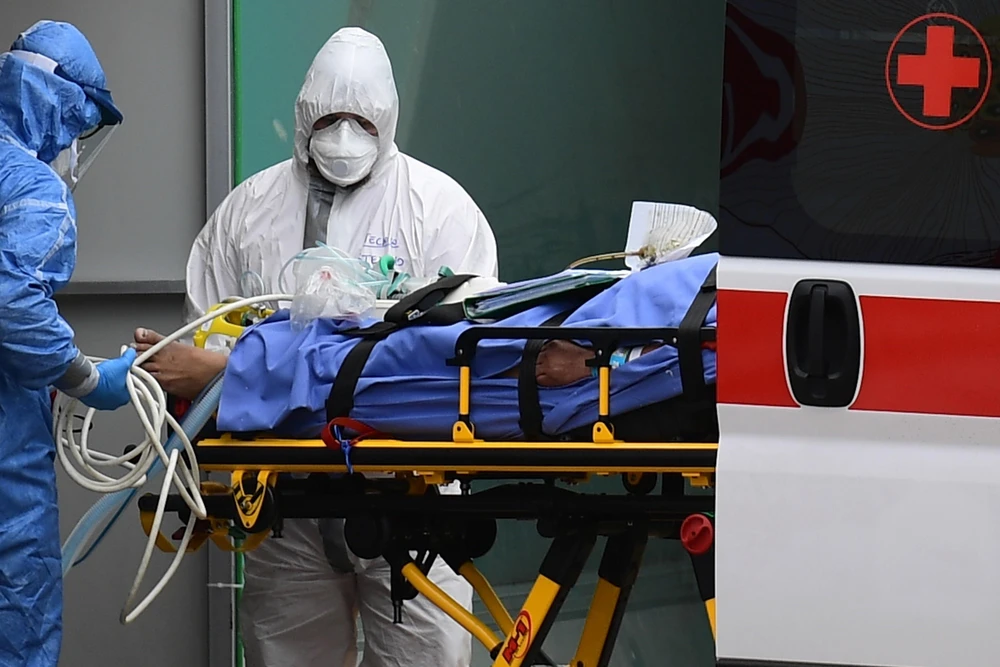 Nhân viên y tế chuyển bệnh nhân nhiễm COVID-19 từ xe cứu thương vào một bệnh viện dã chiến ở Lombardy, Italy. (Ảnh: AFP/TTXVN)