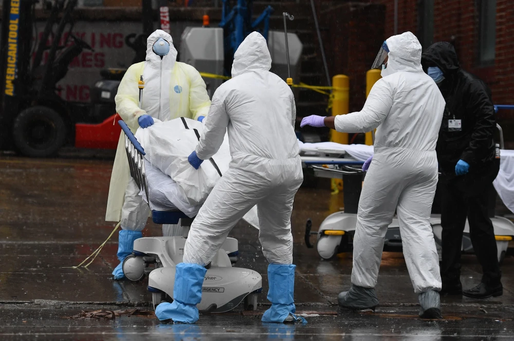 Nhân viên y tế chuyển thi thể bệnh nhân mắc COVID-19 ra nhà xác dã chiến bên ngoài một bệnh viện ở New York, Mỹ. (Ảnh: AFP/TTXVN)