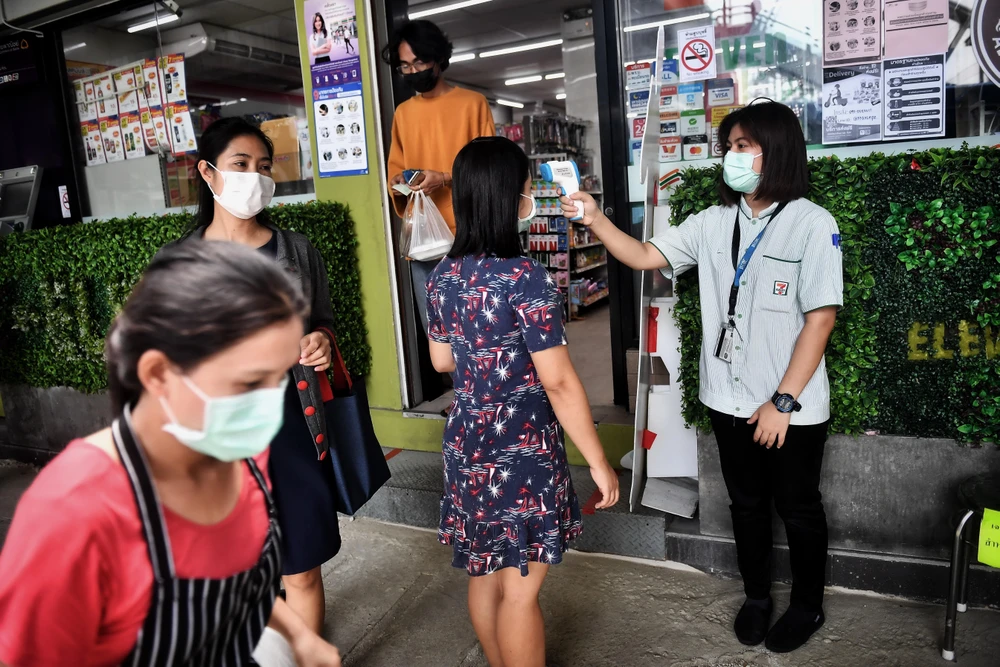 Kiểm tra thân nhiệt cho người dân tại Bangkok, Thái Lan. (Ảnh: AFP/TTXVN)