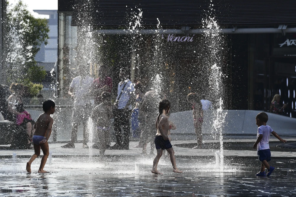 Trẻ em chơi đùa bên vòi phun nước để tránh nắng nóng tại Milan, Italy, ngày 26/6/2019. (Ảnh: AFP/ TTXVN)