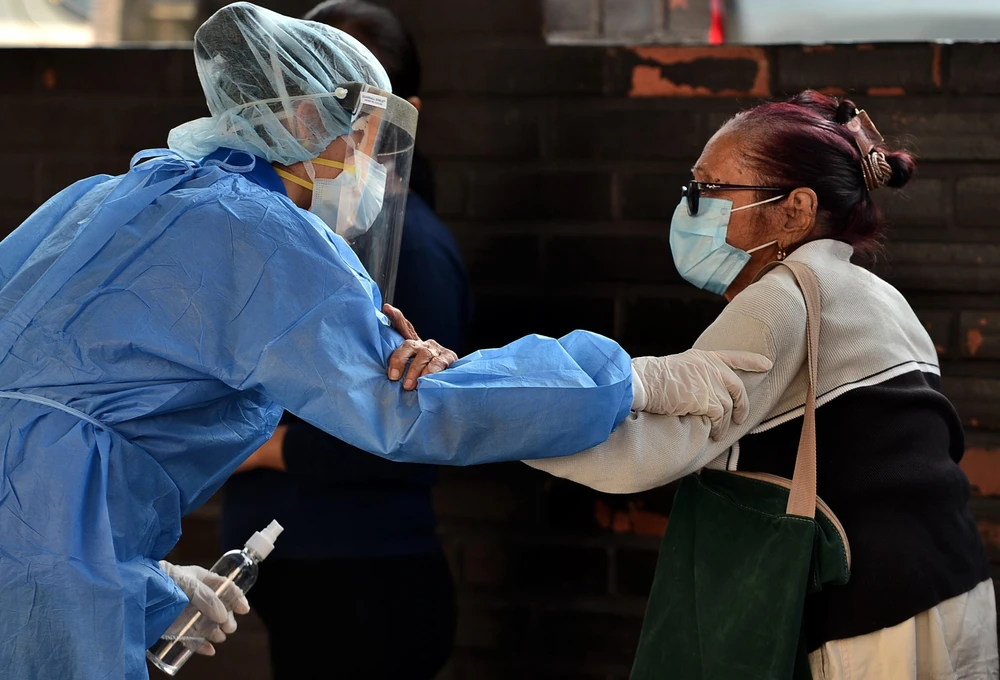 Nhân viên y tế giúp đỡ một bệnh nhân nhiễm COVID-19 tại bệnh viện ở Tegucigalpa, Honduras. (Ảnh: AFP/TTXVN)