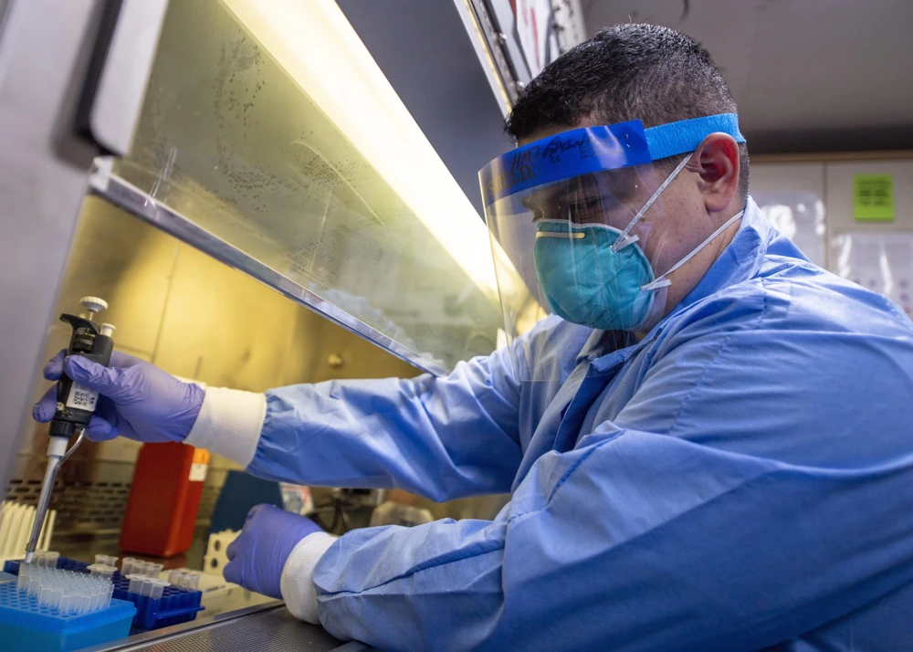 Nhân viên y tế tiến hành xét nghiệm mẫu bệnh phẩm COVID-19 trong phòng thí nghiệm. (Ảnh: AFP/TTXVN)