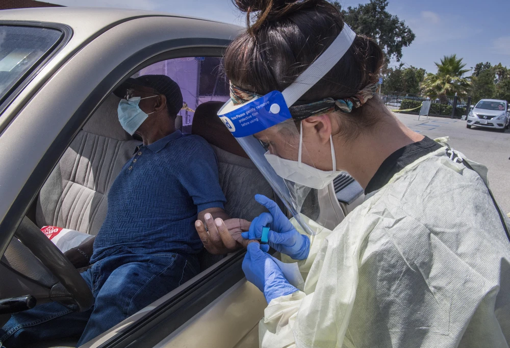 Nhân viên y tế lấy mẫu xét nghiệm COVID-19 cho người dân tại Inglewood, California (Mỹ). (Ảnh: AFP/TTXVN)