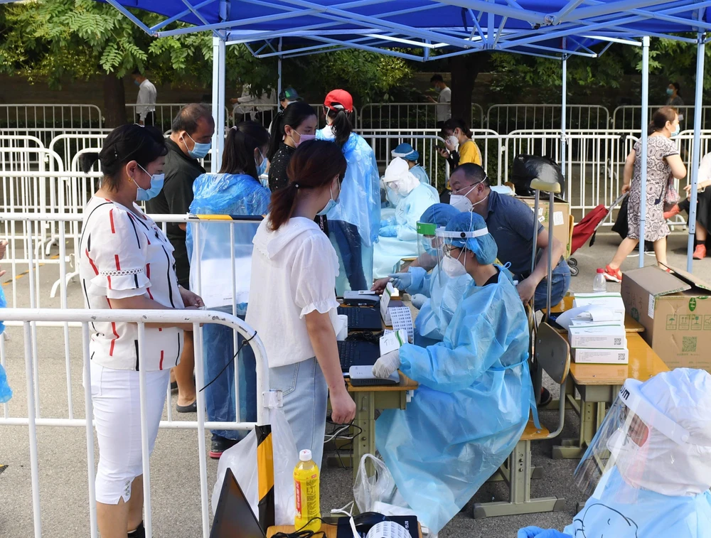 Nhân viên y tế lấy mẫu dịch xét nghiệm COVID-19 cho người dân ở Bắc Kinh, Trung Quốc ngày 26/6. (Ảnh: THX/TTXVN)