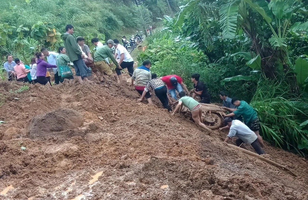 Người dân hỗ trợ đưa xe máy của chị Lò Thị Châu (ở tỉnh Lai Châu) từ dưới vực lên. (Ảnh: TTXVN phát)