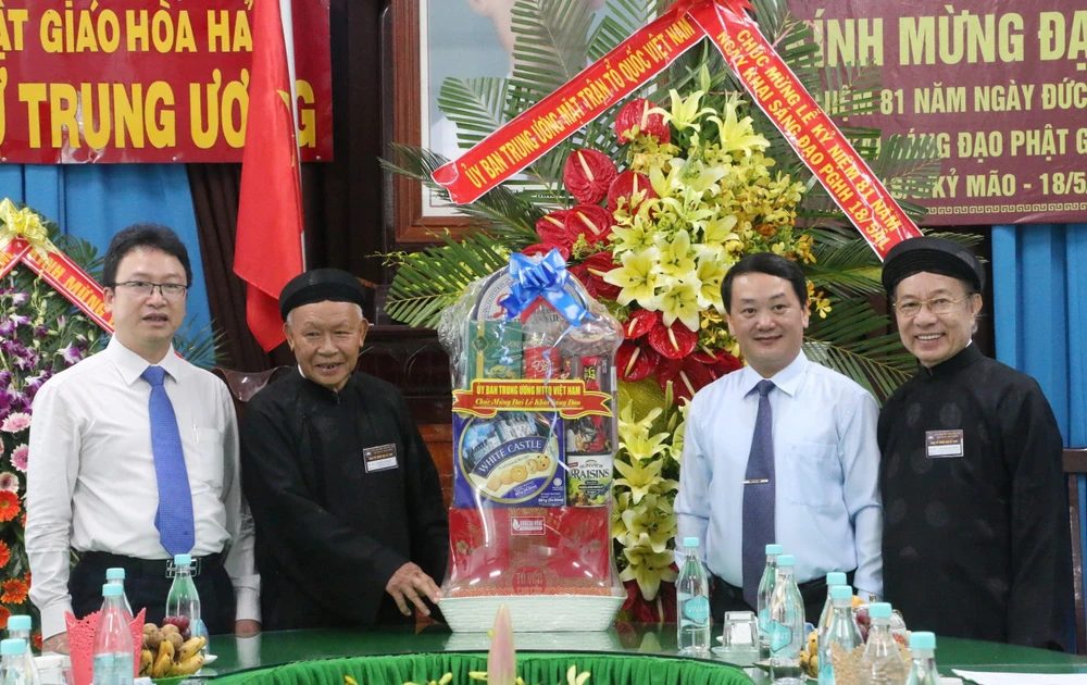 Phó Chủ tịch-Tổng Thư ký Ủy ban Trung ương MTTQ Việt Nam Hầu A Lềnh (thứ 2 phải qua) tặng quà chúc mừng đại lễ kỷ niệm 81 năm Ngày khai sáng đạo Phật giáo Hòa Hảo. (Ảnh: Công Mạo/TTXVN)