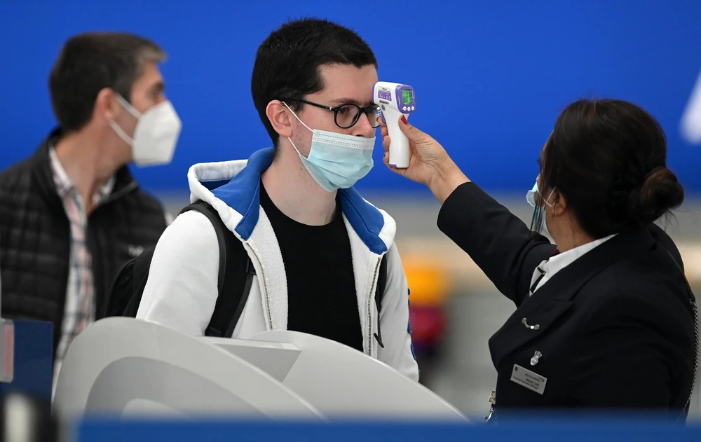 Kiểm tra thân nhiệt phòng lây nhiễm COVID-19 tại sân bay Heathrow ở London, Anh. (Ảnh: AFP/TTXVN)