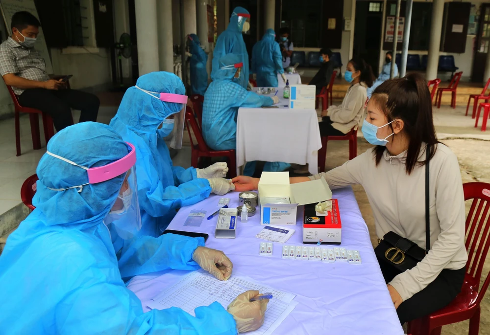 Các cán bộ y tế tiến hành xét nghiệm nhanh COVID-19 cho người dân ở thành phố Đông Hà trở về từ vùng có dịch. (Ảnh: Hồ Cầu/TTXVN)