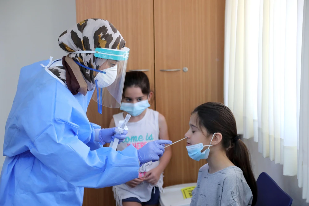 Nhân viên y tế lấy mẫu dịch xét nghiệm COVID-19 cho trẻ em tại thành phố Or Yehuda, Israel. (Ảnh: THX/TTXVN)