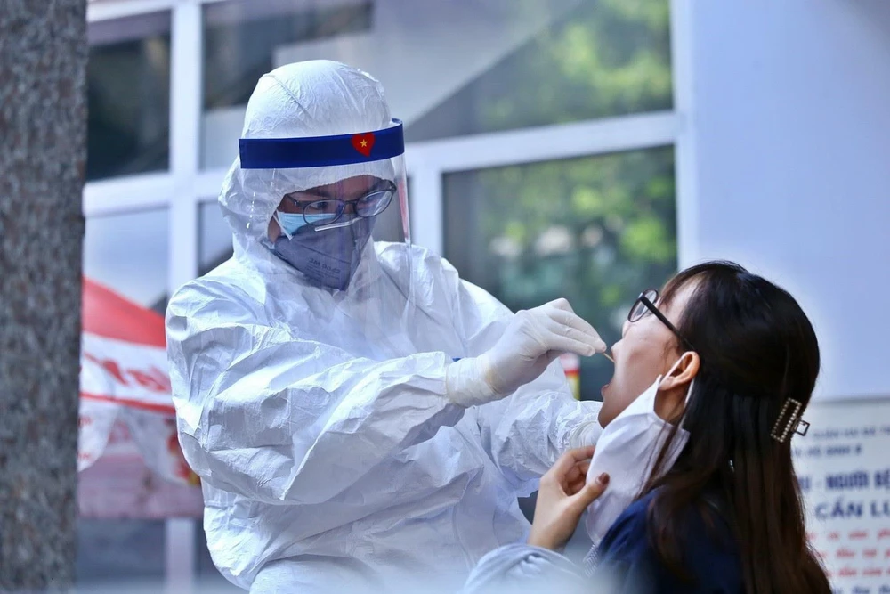Nhân viên y tế lấy mẫu dịch hầu họng để xét nghiệm bằng phương pháp RT-PCR cho người dân trở về từ Đà Nẵng tại Nhà Hộ Sinh B - Trung Tâm Y Tế quận Hai Bà Trưng. (Ảnh: Minh Quyết/TTXVN)