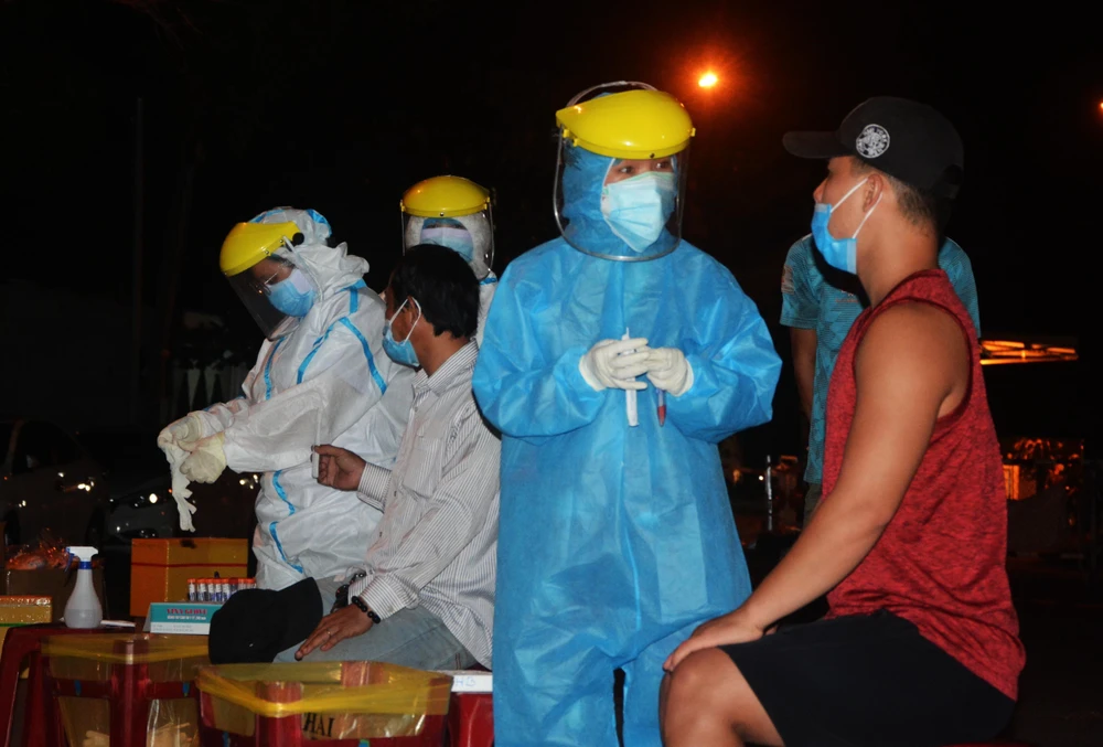 Nhân viên y tế đang lấy mẫu xét nghiệm của người dân tại cảng cá Thọ Quang (Đà Nẵng). (Ảnh: Văn Dũng/TTXVN)