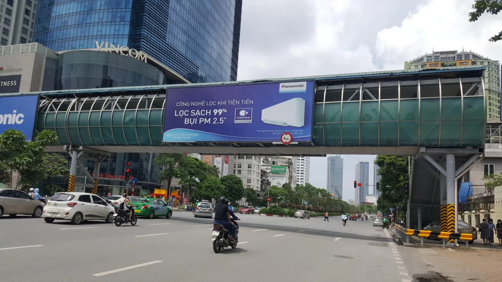 Bảng quảng cáo vi phạm tại cầu vượt dành cho người đi bộ đường Nguyễn Chí Thanh (quận Đống Đa). (Ảnh: Đinh Thuận/TTXVN)