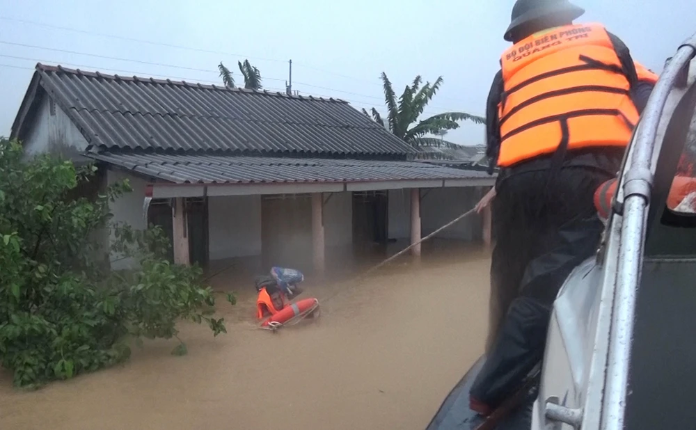 Bộ đội Biên phòng tỉnh Quảng Trị di dời những người dân bị mắc kẹt trong lũ đến nơi an toàn. (Ảnh: Hồ Cầu/TTXVN)