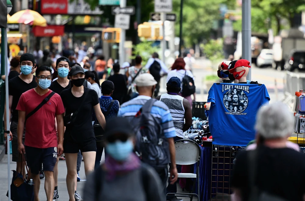 Người dân đeo khẩu trang phòng COVID-19 khi di chuyển trên đường phố tại New York, Mỹ. (Ảnh: AFP/TTXVN)