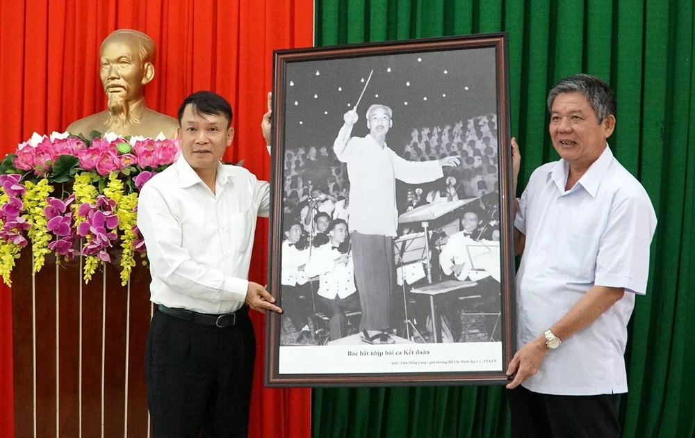 Tổng Giám đốc Thông tấn xã Việt Nam Nguyễn Đức Lợi (bên trái) tặng bức ảnh Bác bắt nhịp bài ca kết đoàn cho lãnh đạo Tỉnh ủy Trà Vinh. (Ảnh: Thanh Hòa/TTXVN)