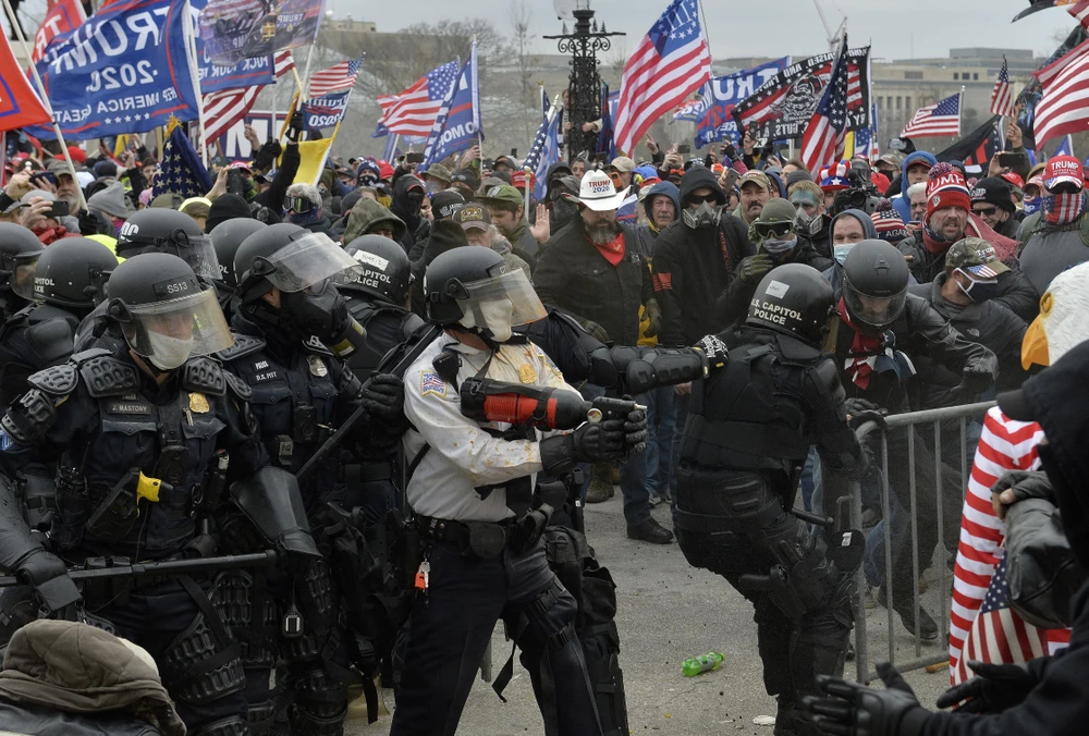 Cảnh sát chặn người biểu tình cố gắng vượt qua hàng rào an ninh để xâm nhập tòa nhà Quốc hội Mỹ. (Ảnh: AFP/TTXVN)