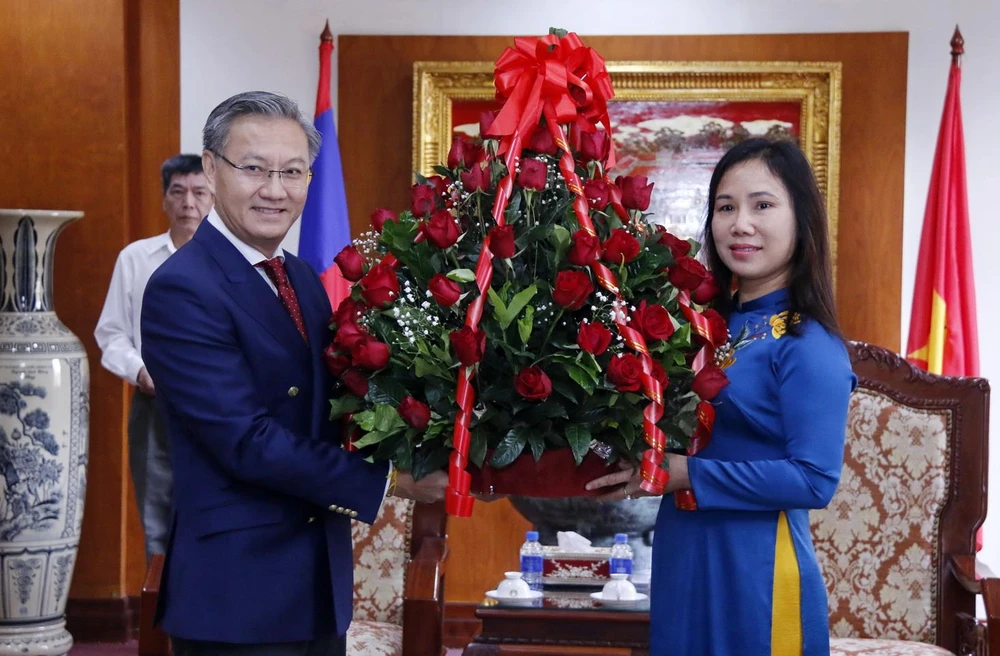 Đồng chí Thongsavane Phomvihane, Ủy viên Tung ương Đảng, Thứ trưởng Bộ Ngoại giao Lào tặng lẵng hoa chúc mừng Đại biện lâm thời Đại sứ quán Việt Nam tại Lào Trịnh Thị Tâm. (Ảnh: Phạm Kiên/TTXVN)