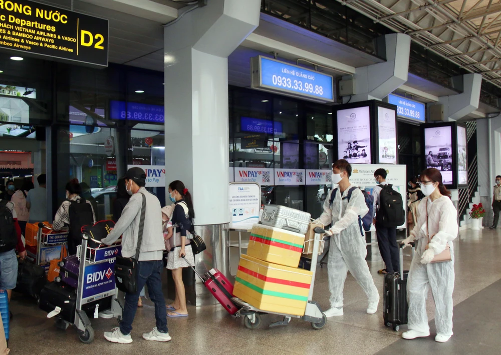Để phòng chống dịch, nhiều hành khách đã chủ động trang bị các bộ đồ bảo hộ khi đến sân bay Tân Sơn Nhất. (Ảnh: Tiến Lực/TTXVN)