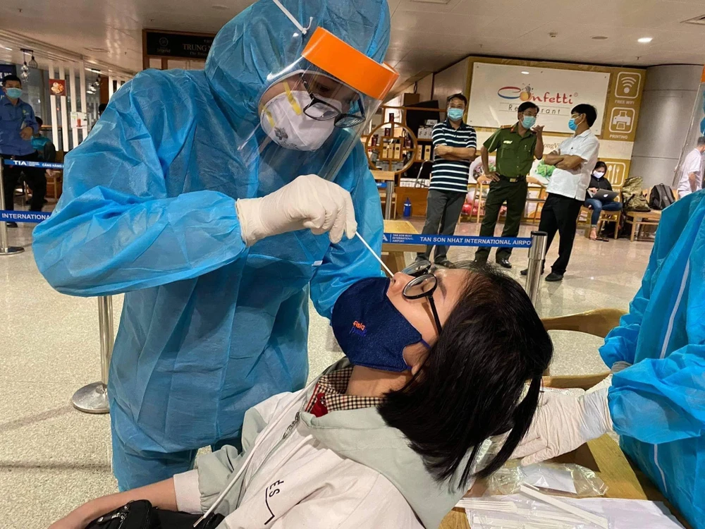 Nhân viên y tế lấy mẫu xét nghiệm cho người làm việc tại sân bay Tân Sơn Nhất. (Ảnh: TTXVN phát)