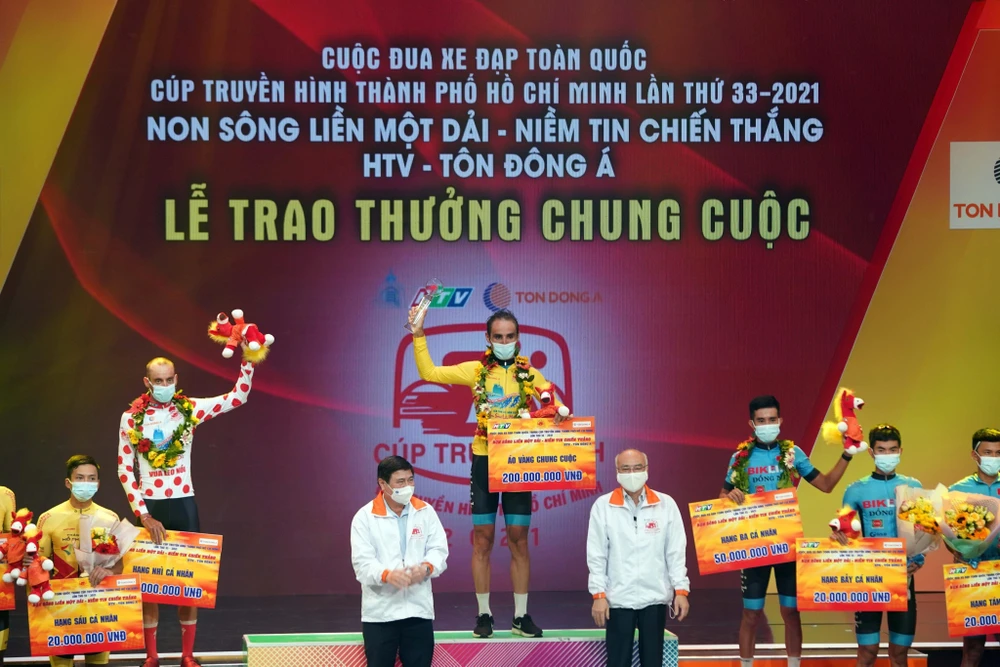 Chủ tịch UBND Thành phố Hồ Chí Minh Nguyễn Thành Phong cùng đại diện Ban tổ chức trao chiếc áo vàng chung cuộc cho vận động viên Loic Desriac. (Ảnh: Thanh Vũ/TTXVN)