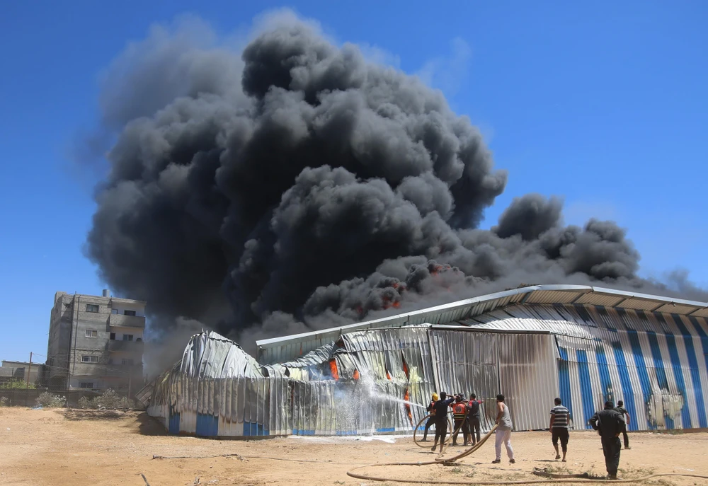 Lính cứu hoả nỗ lực dập lửa căn nhà bị trúng oanh kích của máy bay Israel tại thành phố Rafah, Dải Gaza ngày 18/5/2021. (Ảnh: THX/TTXVN)