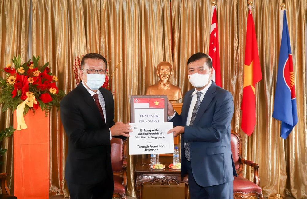 Đại sứ Mai Phước Dũng (phải) tiếp nhấn tượng trưng lô hàng do Quỹ Tamasek trao tặng. (Ảnh: Lê Dương/TTXVN)