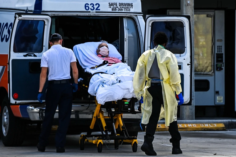 Nhân viên y tế chuyển bệnh nhân COVID-19 tới bệnh viện tại Miami, Mỹ. (Ảnh: AFP/TTXVN)
