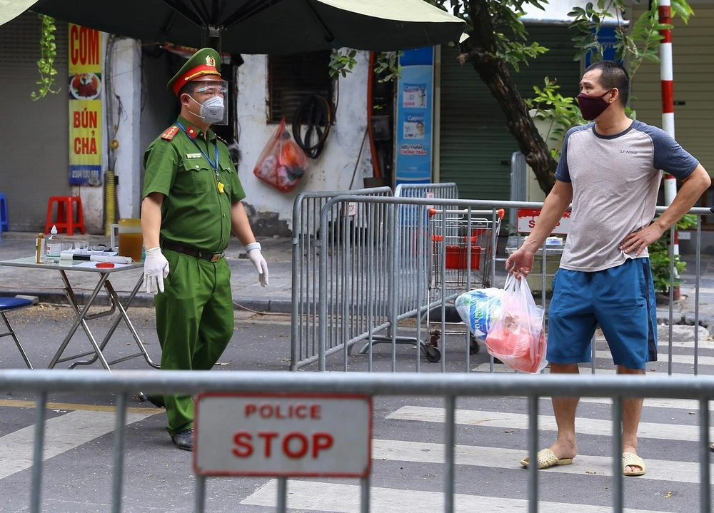 Công an hướng dẫn người dân đưa đồ tiếp tế cho người thân trong Bệnh viện hữu nghị Việt Đức qua cổng đường Tràng Thi. (Ảnh: Hoàng Hiếu/TTXVN)