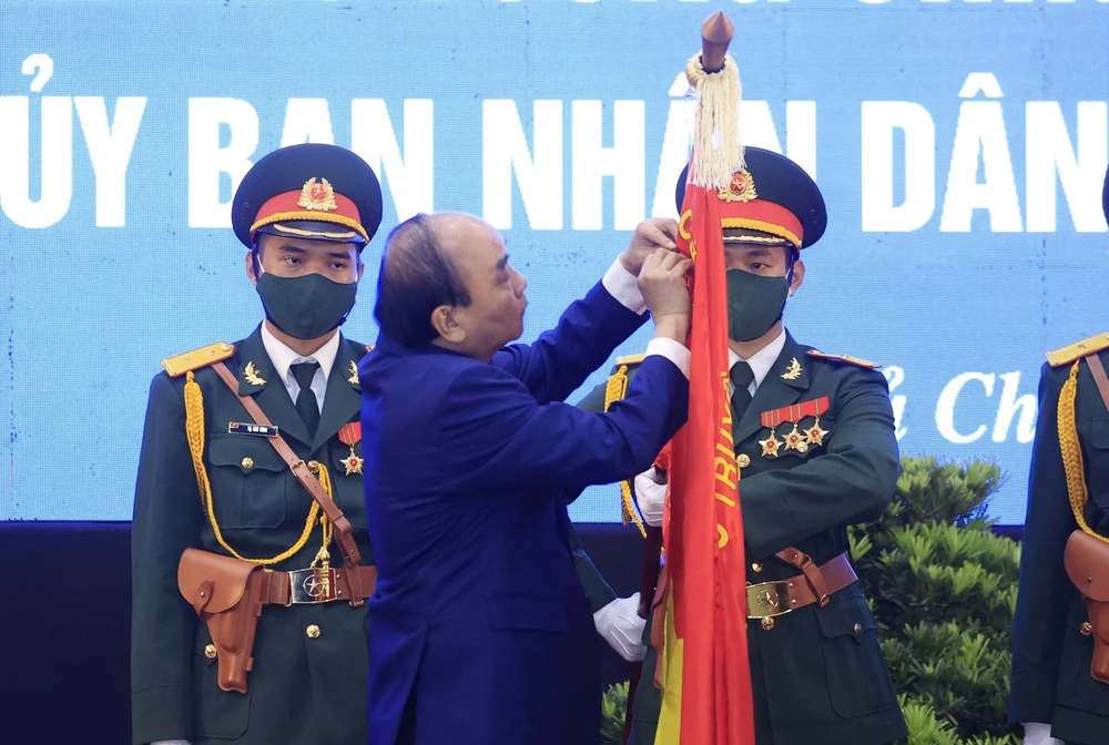 Chủ tịch nước Nguyễn Xuân Phúc gắn Huân chương Lao động hạng Ba lên lá cờ truyền thống của huyện Củ Chi. (Ảnh: Thống Nhất/TTXVN)