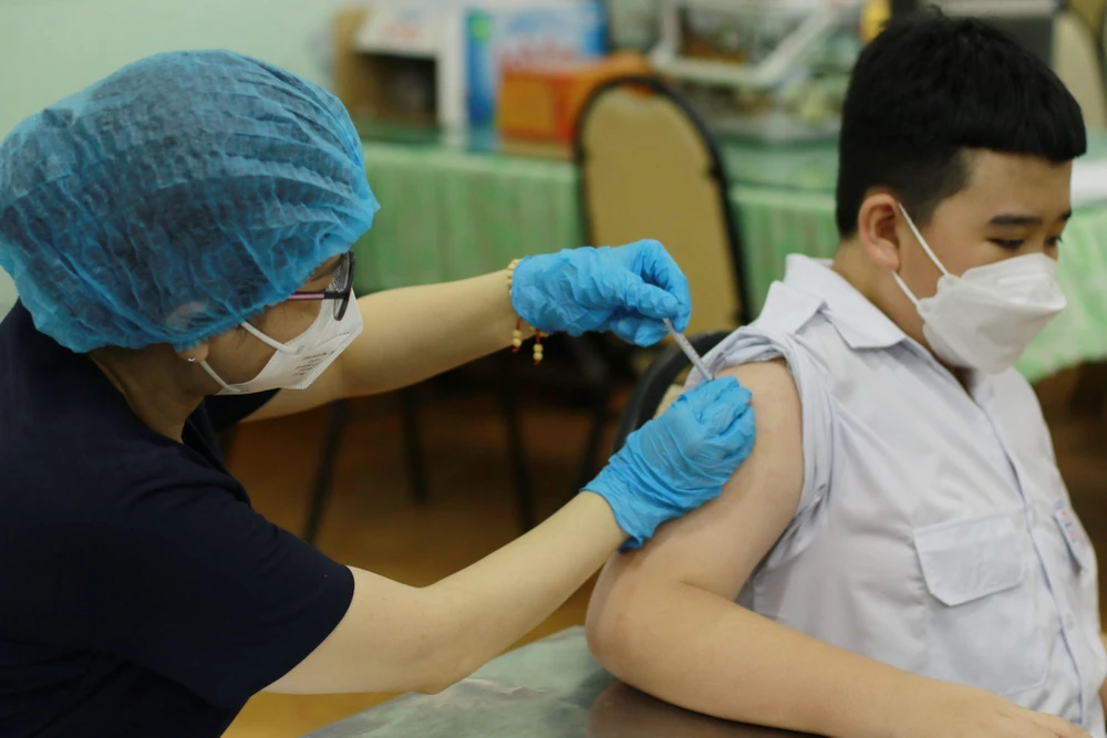 Nhân viên y tế tiêm vaccine phòng COVID-19 cho học sinh trường Trung học cơ sở Hồng Bàng (Quận 5). (Ảnh: Thu Hương/TTXVN)