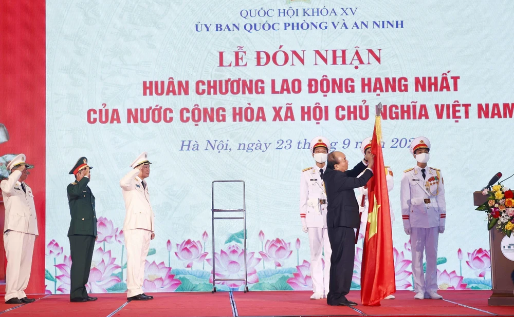 Chủ tịch nước Nguyễn Xuân Phúc gắn Huân chương Lao động hạng Nhất lên cờ truyền thống của Ủy ban Quốc phòng và An ninh của Quốc hội. (Ảnh: Doãn Tấn/TTXVN)