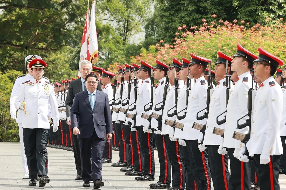 Thủ tướng Phạm Minh Chính và Thủ tướng Singapore Lý Hiển Long duyệt đội danh dự. (Ảnh: Dương Giang/TTXVN)