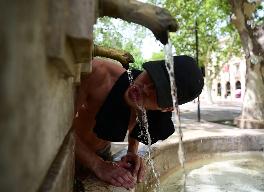 Người dân uống nước từ vòi để tránh nóng tại Xativa, Valencia, Tây Ban Nha, ngày 10/8. (Ảnh: AFP/TTXVN)