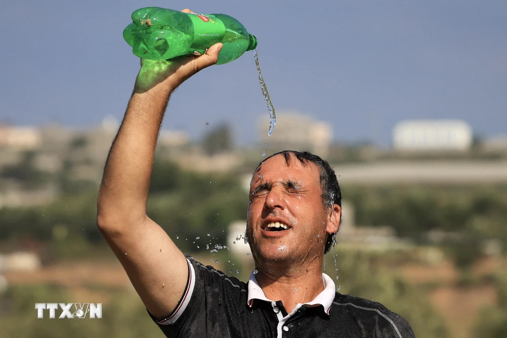 Một người đàn ông dội nước lên đầu làm mát dưới thời tiết nắng nóng tại Dải Gaza ngày 19/7/2023. (Ảnh: AFP/TTXVN)