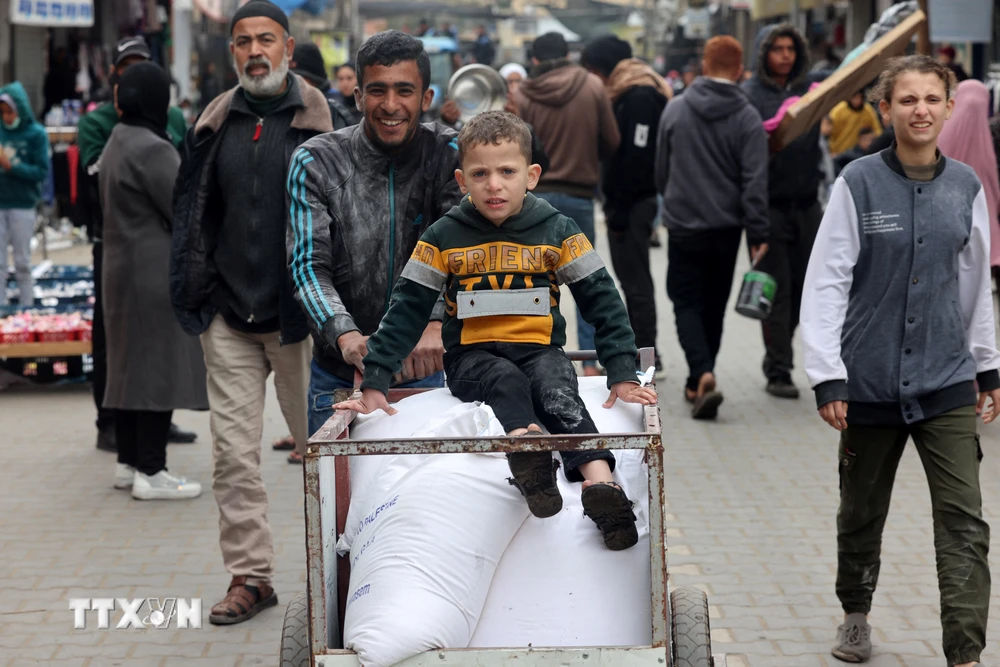 Người tị nạn Palestine nhận hàng cứu trợ từ UNRWA ở thành phố Rafah, Dải Gaza ngày 28/1. (Ảnh: AFP/TTXVN)