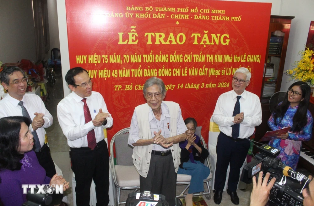 Bí thư Thành ủy Thành phố Hồ Chí Minh Nguyễn Văn Nên trao huy hiệu Đảng cho nhà thơ Lê Giang và nhạc sỹ Lư Nhất Vũ. (Ảnh: Chí Tưởng/TTXVN)