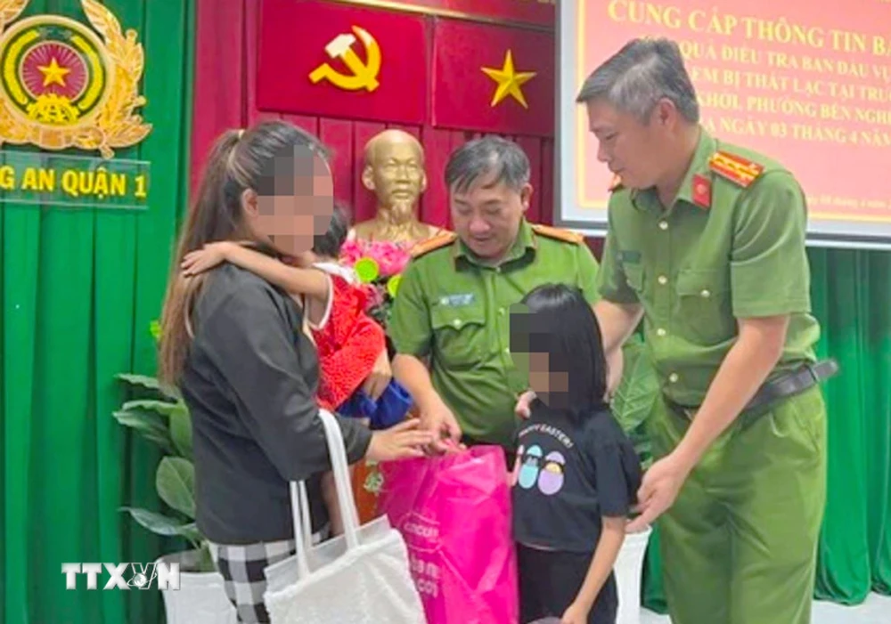 Lực lượng Công an Thành phố Hồ Chí Minh trao trả hai cháu bé về với gia đình chị Nguyễn Thị Chi. (Ảnh: TTXVN phát)