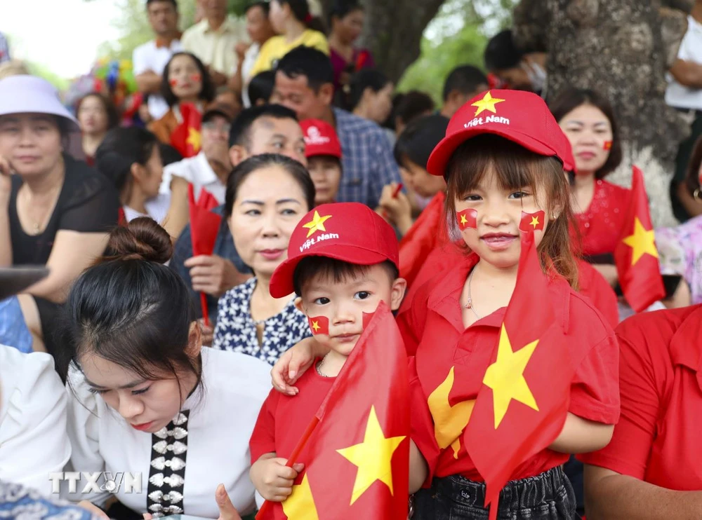 Những em nhỏ với trang phục rực rỡ cờ hoa theo người lớn đi xem diễu binh, diễu hành. (Ảnh: Xuân Tư/TTXVN)