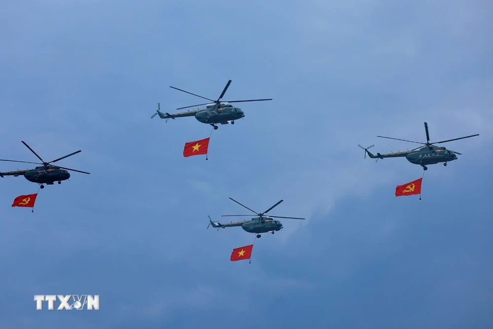 Máy bay trực thăng mang cờ Đảng, cờ Tổ quốc bay qua Lễ đài. (Ảnh: Dương Giang/TTXVN)